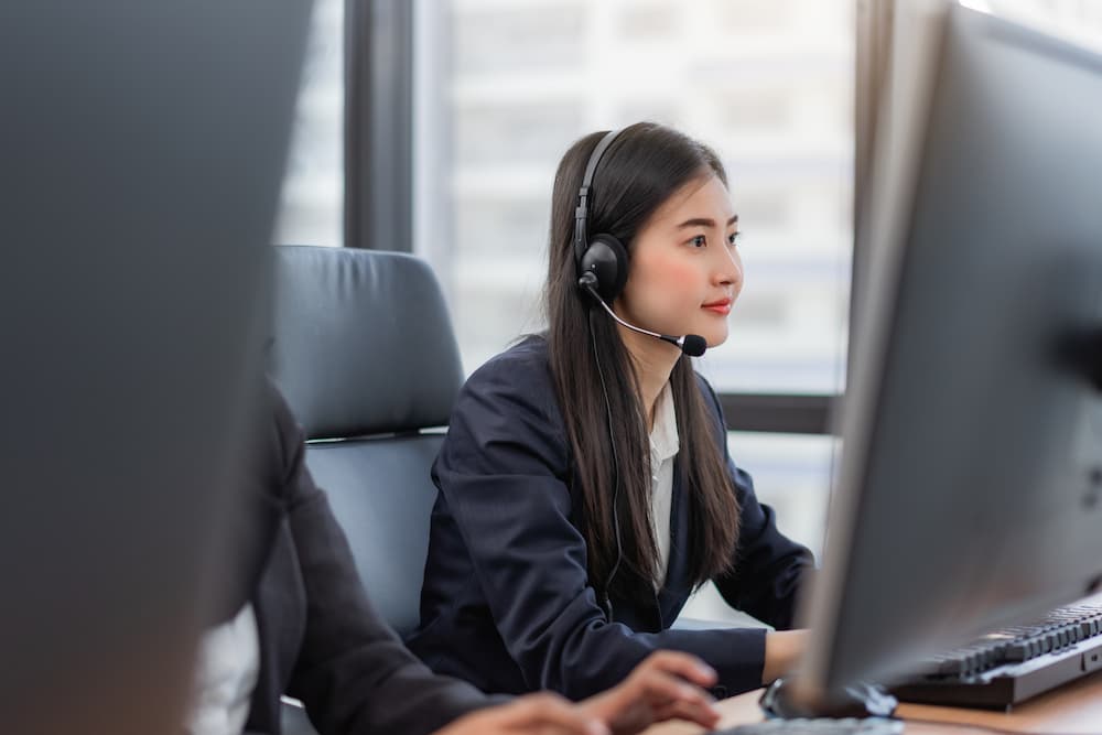 happy-smiling-operator-asian-woman-customer-service-agent-with-headsets-working-computer-call-center-talking-with-customer-assisting-resolve-problem-with-her-service-mind